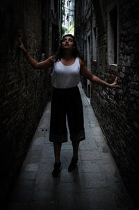 Young woman standing on street amidst buildings