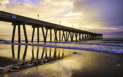 Pier over sea against sky during sunset