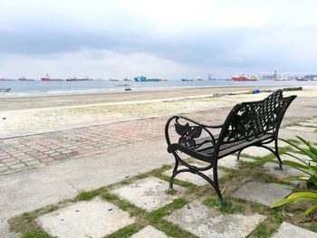 Empty chairs on beach against sky