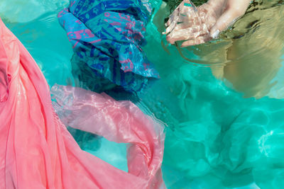 Cropped hand of woman holding pyramid crystal in swimming pool