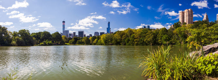 Panoramic view of lake and trees against sky in city on sunny day at central park