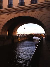 Arch bridge over river in city against sky