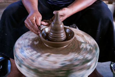 Midsection of person making pot at workshop