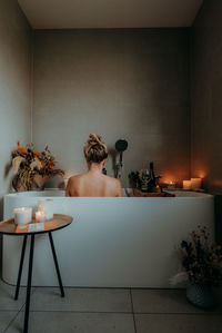 Rear view of shirtless man sitting on table at home