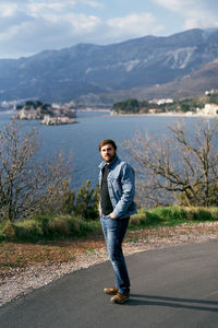 Portrait of young man standing on mountain against sky