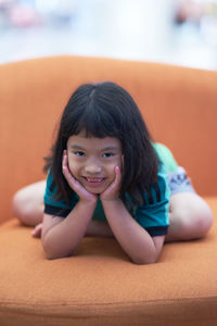 Portrait of smiling girl sitting on sofa at home