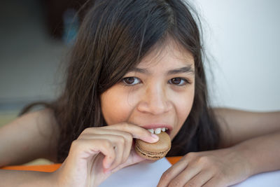 Close-up portrait of girl eating macaroon