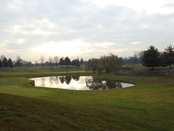 View of golf course against cloudy sky