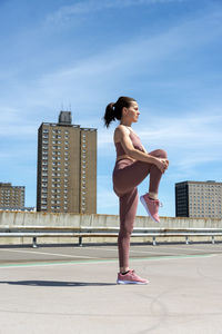 Sporty woman doing a leg stretch warm up exercise outside, urban setting.