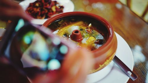 Cropped hands photographing chicken soup on table