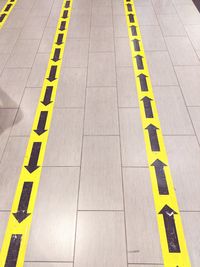 High angle view of arrow signs on tiled floor