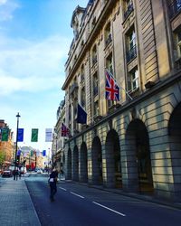 Man walking on road in city against sky