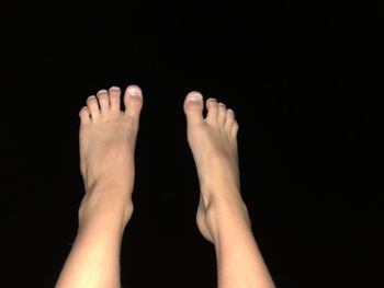 Low section of woman legs against black background