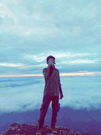 Man holding stuffed toy against face while standing on mountain