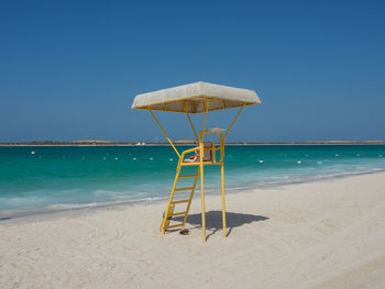 Lifeguard hut on beach against clear blue sky