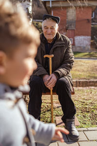 Senior man looking at grandson while sitting on bench in park