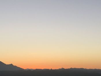 Scenic view of silhouette mountains against clear sky during sunset