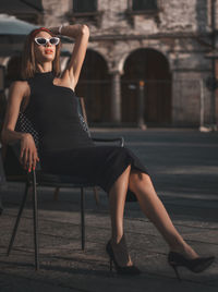 Full length of young woman sitting on street