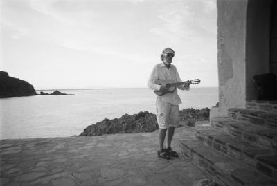 Full length of man standing on sea shore against sky