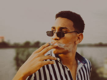 Portrait of young man drinking water against sky