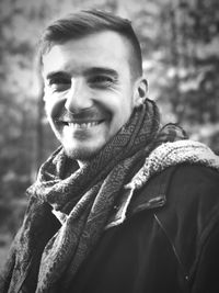 Portrait of smiling young man wearing scarf in forest