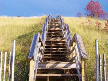 Low angle view of wooden staircase on grass against sky