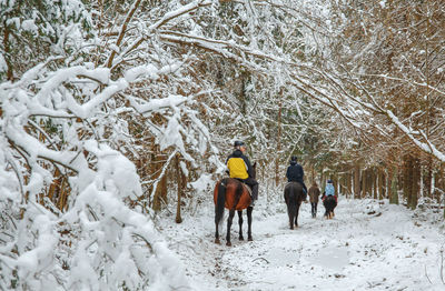 Rear view of people walking on snow covered field