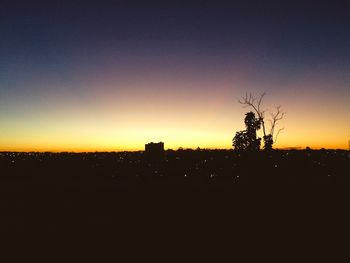 Silhouette trees on field against clear sky