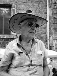 Man wearing sunglasses and hat against wall