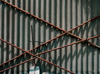 Full frame shot of rusty metal fence against wall