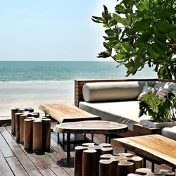 Table and chairs at beach against clear sky