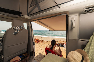 Woman sitting on beach seen through window