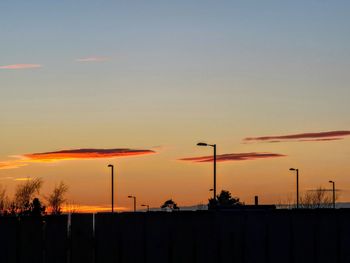 Silhouette street light against orange sky