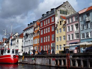 Buildings by river against sky in city