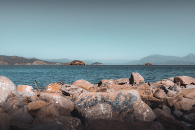 Rocks by sea against clear sky