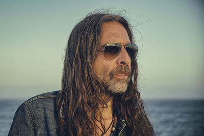 Senior man in sunglasses against sea during sunset