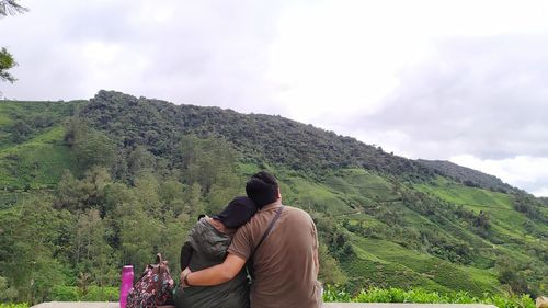 Rear view of couple on mountain against sky