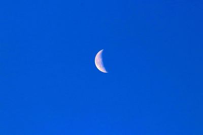 Low angle view of moon against clear blue sky