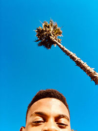 Low angle portrait of man against clear blue sky