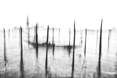 Wooden posts in water against sky