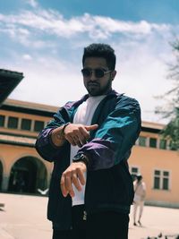 Young man wearing sunglasses standing against built structure