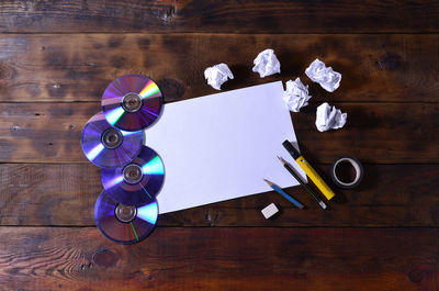 High angle view of paper with discs and school supplies on table