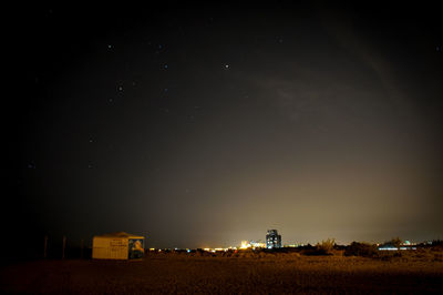 Illuminated field against sky at night