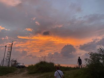 People standing on field against sky during sunset