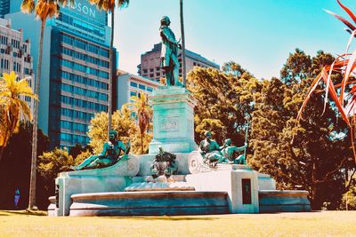 Statue by building in city against sky