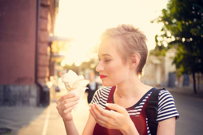 Portrait of woman holding ice cream in city