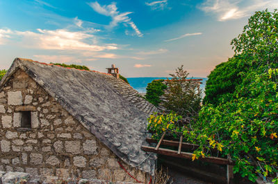 Stone wall of building and trees against sky