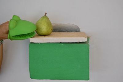 Close-up of green fruits on table against white wall