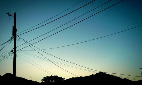 Low angle view of electricity pylon against blue sky