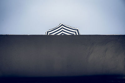 Low angle view of umbrella on wall against clear sky